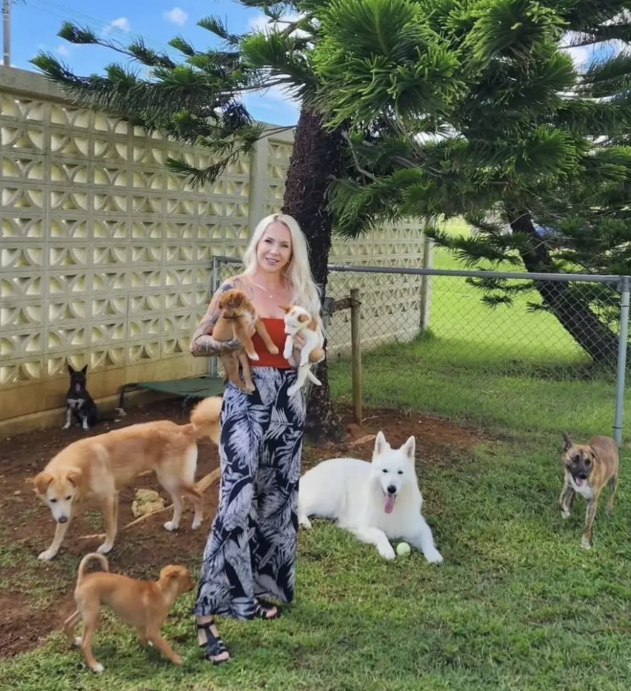 Nicole holding rescue puppies with dogs around her in Okinawa